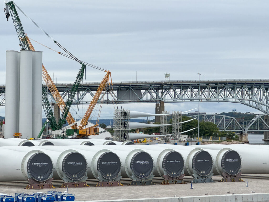 Parts of wind turbines are organized at New London's State Pier.
