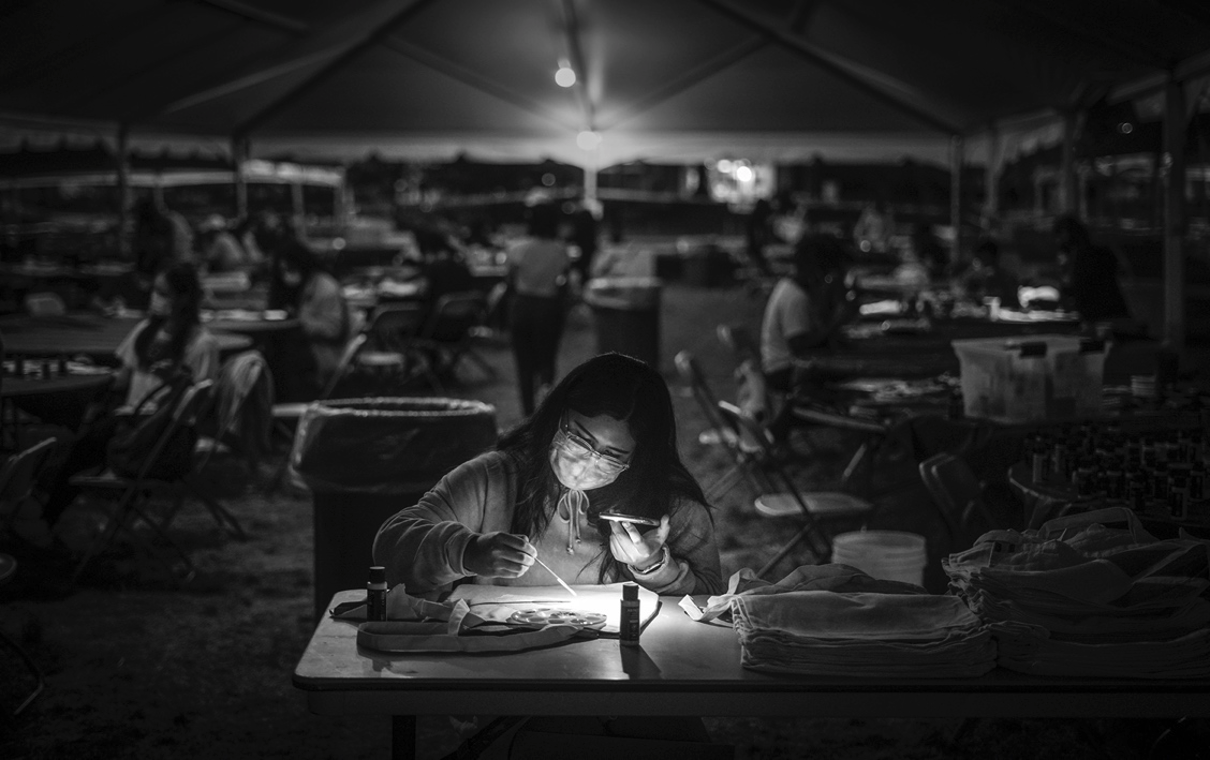 Flo Evardo paints a tote bag under the Student Union lawn tent. Photo by Maggie Chafouleas, Class of 2022